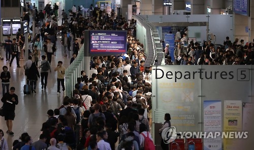 資料圖片:在仁川機場等待出境的遊客們排起了長龍。(韓聯社)