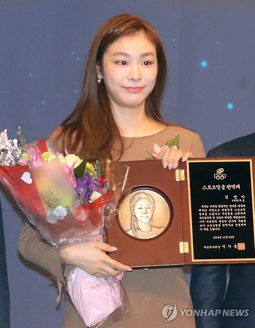 11月23日,在首爾奧林匹克公園酒店,金妍兒手拿“2016體育英雄名譽殿堂”入殿紀念牌接受媒體拍照。(韓聯社)