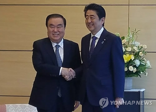 5月18日,在東京,南韓總統特使文喜相(左)與日本首相安倍晉三在會談前握手合影。(韓聯社)