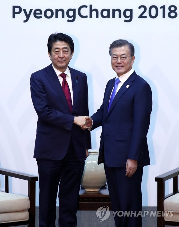 2月9日,在江原道龍平度假村,南韓總統文在寅(右)在歡迎招待會上同到訪的日本首相安倍晉三握手。(韓聯社)