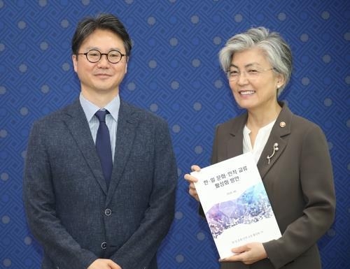 8月16日,在外交部大樓,外長康京和(右)接到韓日人文交流小組組長李勳提交的報告。(韓聯社)