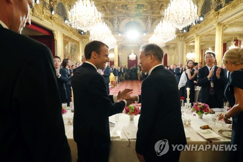 當地時間10月15日,在法國總統府愛麗舍宮,南韓總統文在寅(右)在法方舉辦的國宴上與法國總統馬克龍握手。(韓聯社)