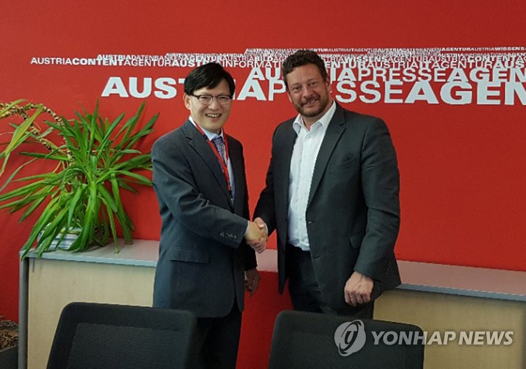 當地時間5月16日,在位於維也納的奧地利通訊社(APA)總部,韓聯社常務理事趙福來(左)與APA相關人士握手合影留念。(韓聯社)