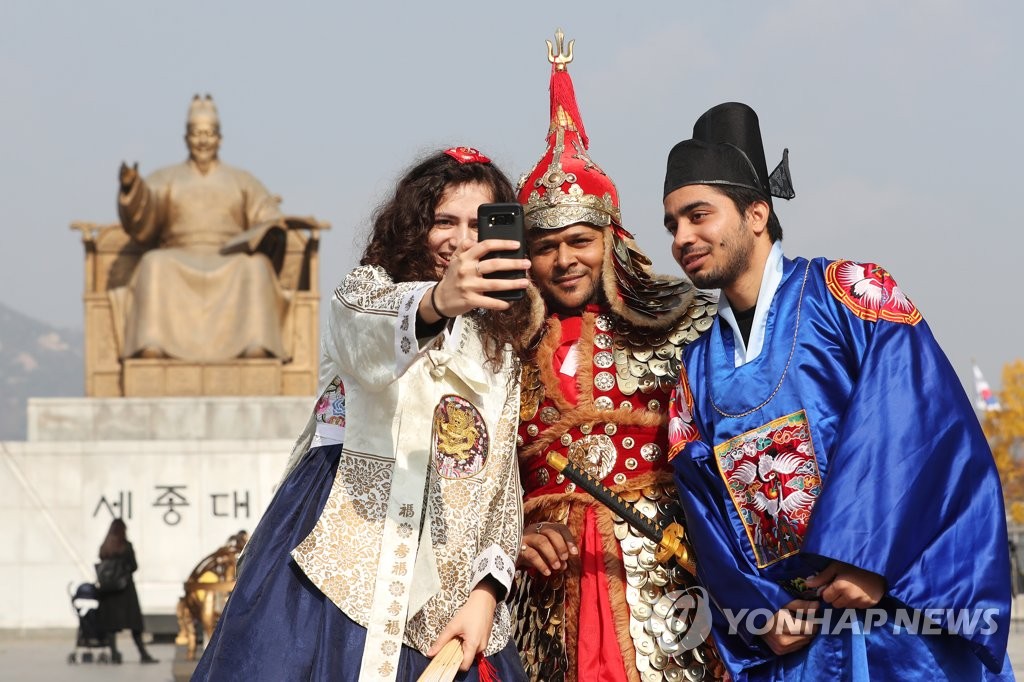 資料圖片:外國遊客在首爾光化門廣場世宗大王銅像前合影留念。(韓聯社)