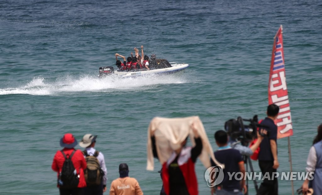 資料圖片:5月16日,在江原道江陵市的鏡浦海灘,遊客正乘坐快艇感受清涼海風。 韓聯社