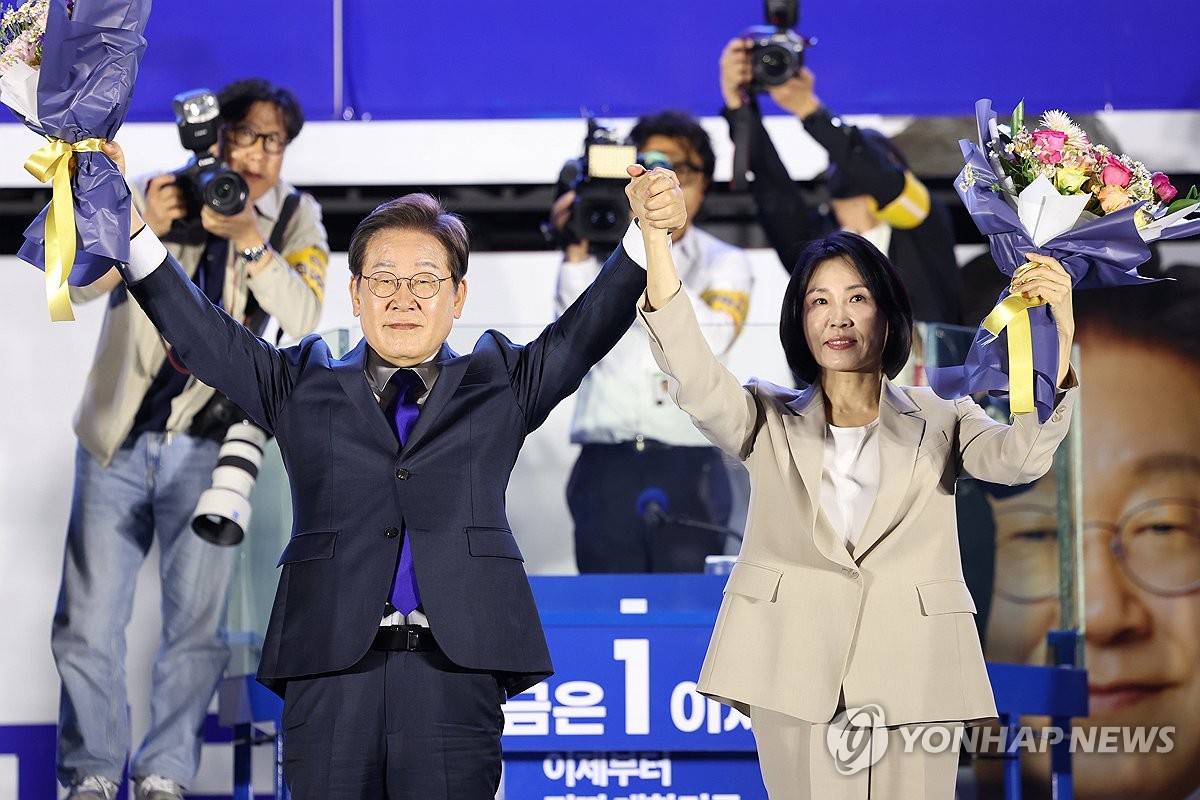 6月4日,在首爾汝矣島國會附近,共同民主黨總統候選人李在明(左)和夫人金惠景高舉雙手向市民致意。李在明當選新任總統已成定局。 韓聯社/聯合採訪團
