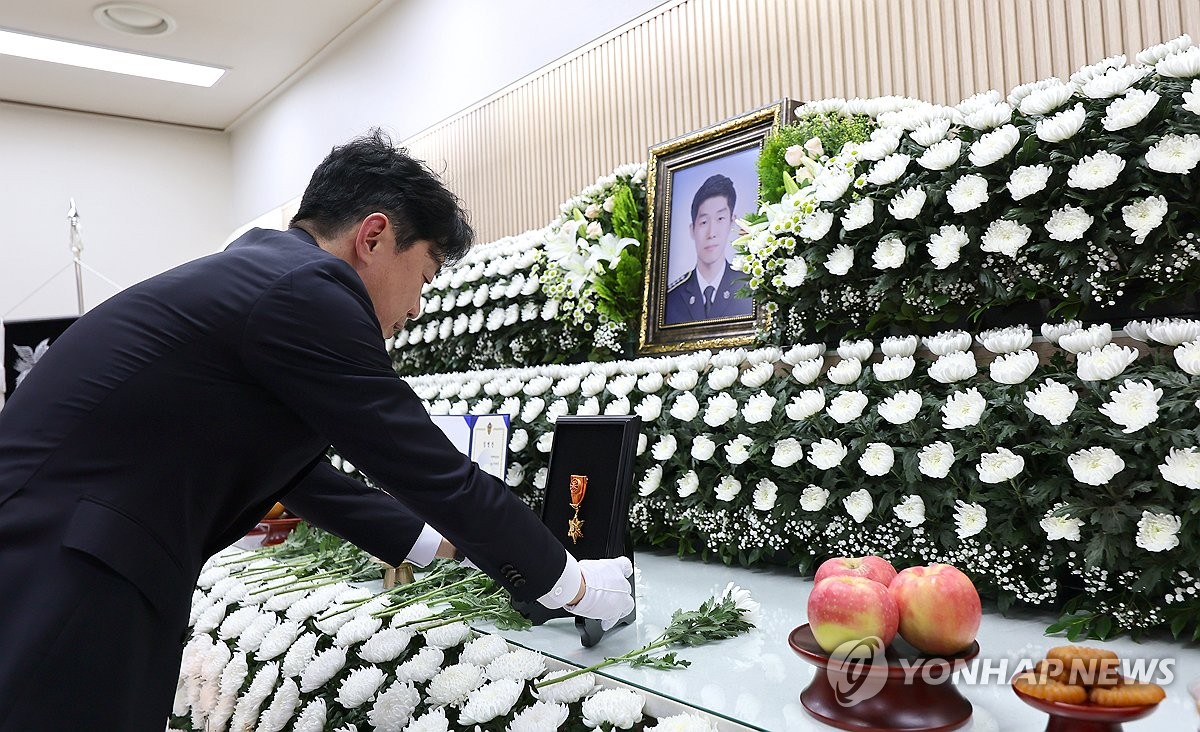 9月12日,在仁川市東區的一殯儀館,總統室秘書室長姜勳植向殉職海警李在錫追授勳章。 韓聯社