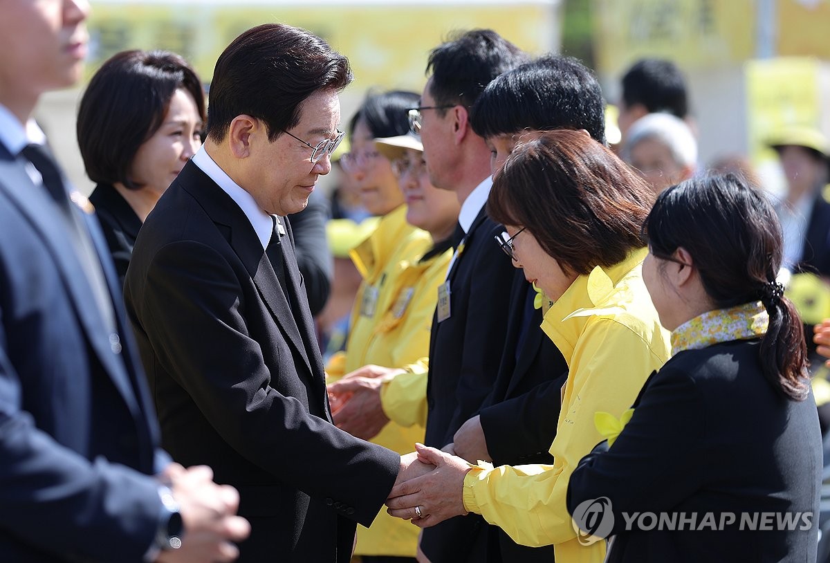 4月16日,在京畿道安山市,李在明(左)在“世越”號沉船事故12週年悼念儀式上與遇難者家屬握手。 韓聯社